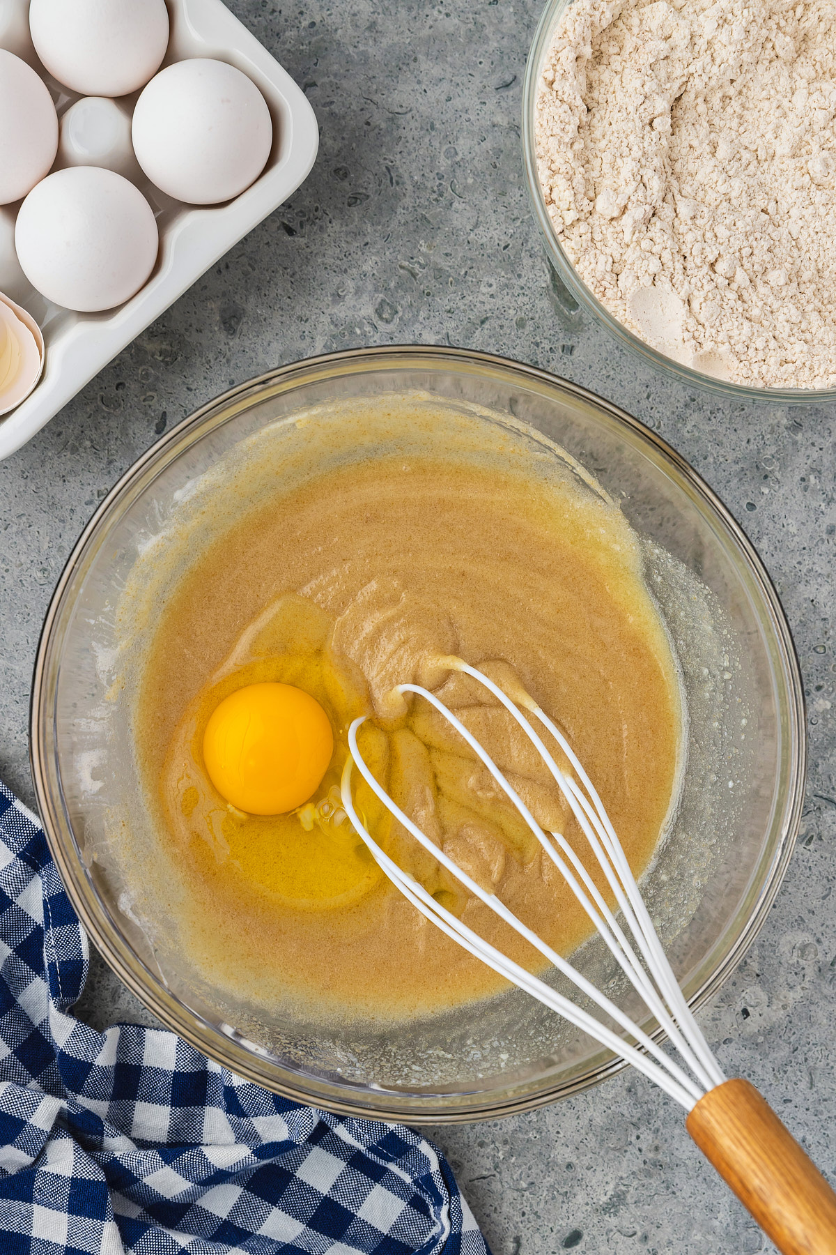 egg added to bowl of banana cake batter with a whisk