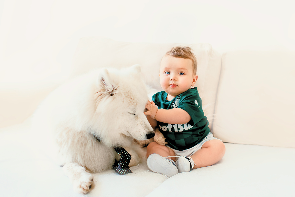 Baby boy sitting up and leaning on dog. Poppyseed Play