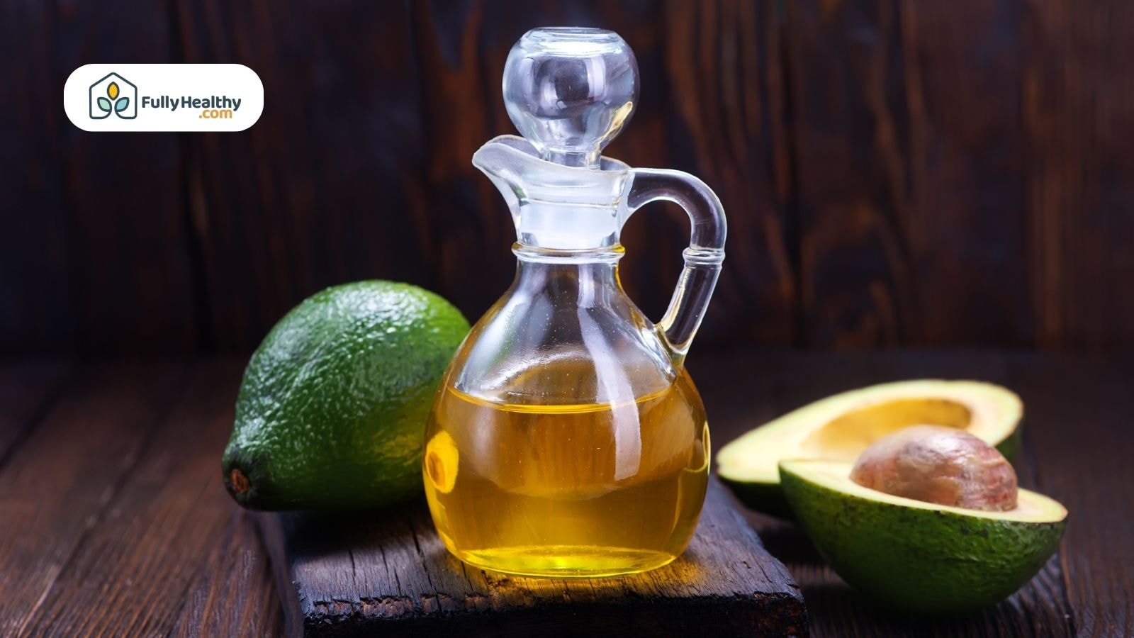 Glass bottle of avocado oil with fresh avocados on wooden surface