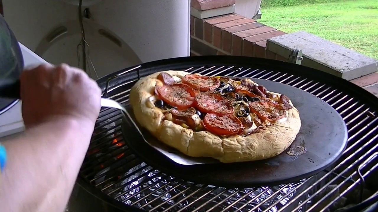 metallic pizza stone with pizza on grill