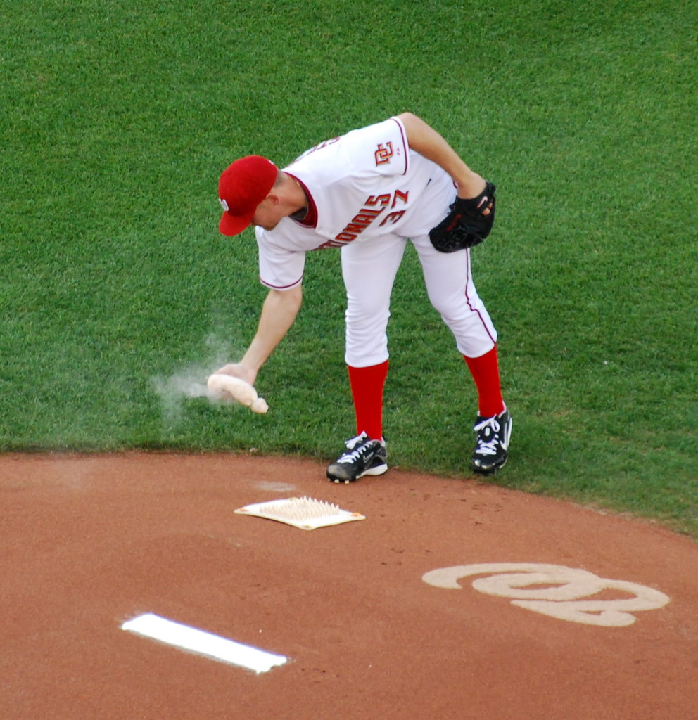 A baseball game with a pitcher holding a rosin bag on the pitcher's mound