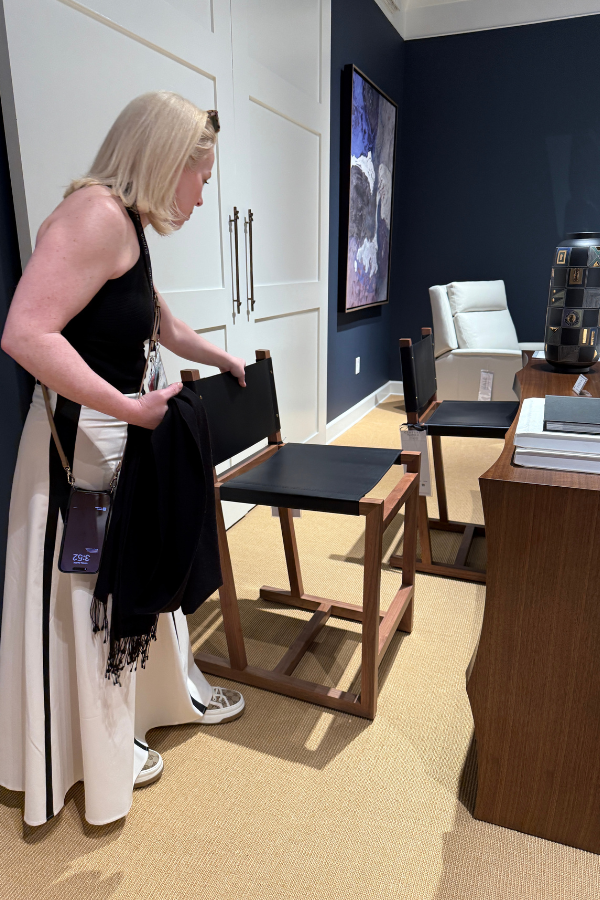 Laura pauses to examine the seat, legs, headrest, and other features of a leather chair without cushions; Shannon was on the same page