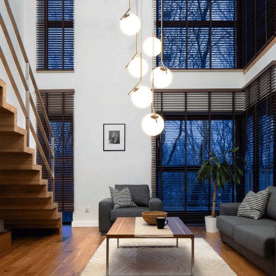 Modern entryway lighting featuring a cascading globe pendant chandelier in a high-ceiling living space, creating a bright and stylish focal point by the staircase.