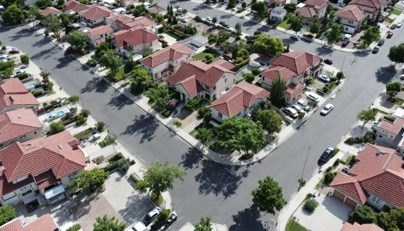 Uma vista aérea de um bairro residencial revela casas organizadas e ruas pavimentadas, refletindo um planejamento urbano eficiente. A imagem destaca a regularização de imóveis, com edificações que seguem as normas do código de obras e um ambiente harmonioso para os proprietários.