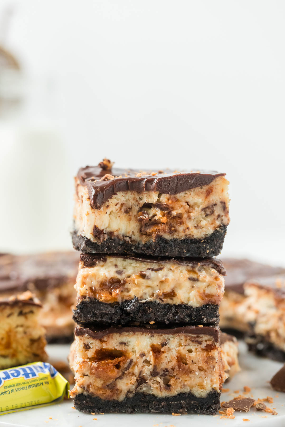 three butterfinger cheesecake bars stacked on top of each other