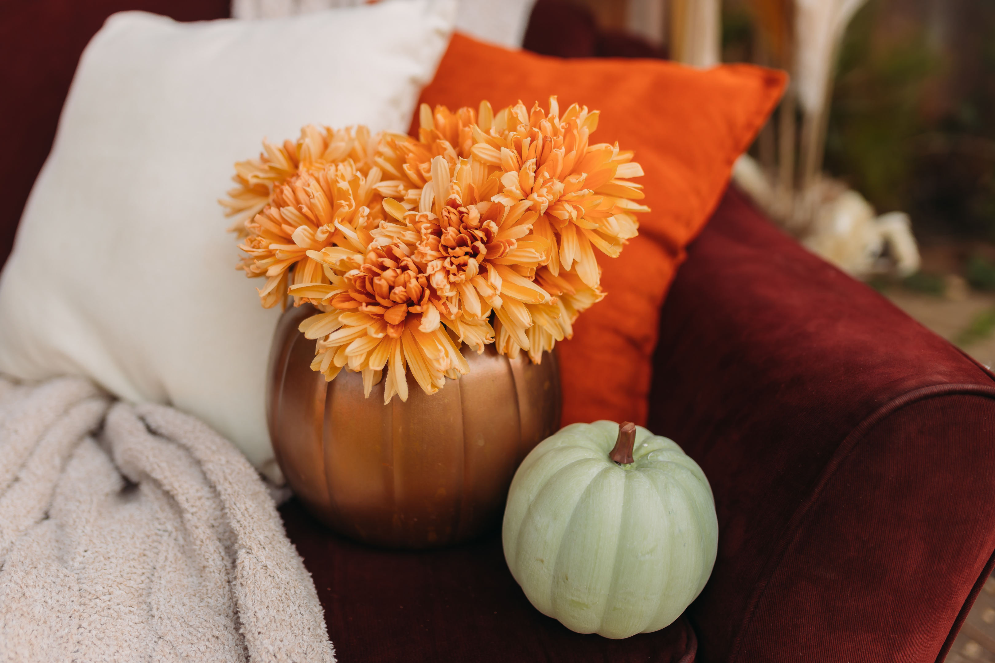 Earthy hues of rusty orange and deep red velvet chair with fall floral arrangement