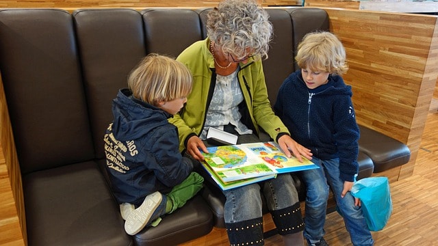 A woman reading with her two children.