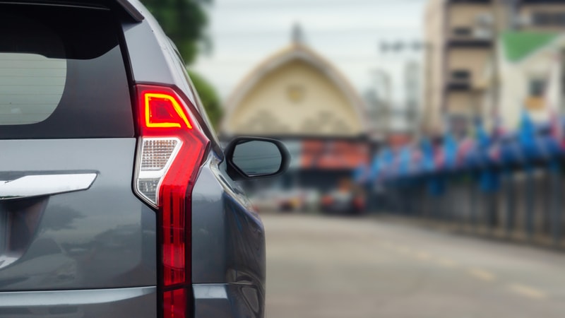 Brake lights lighting up on a moving car during sudden stop, daytime scene