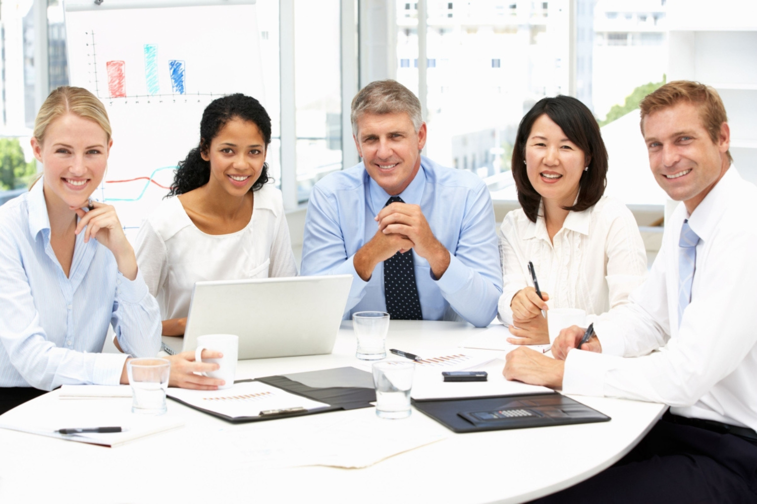 A group of business professionals are sitting around a table in a meeting.