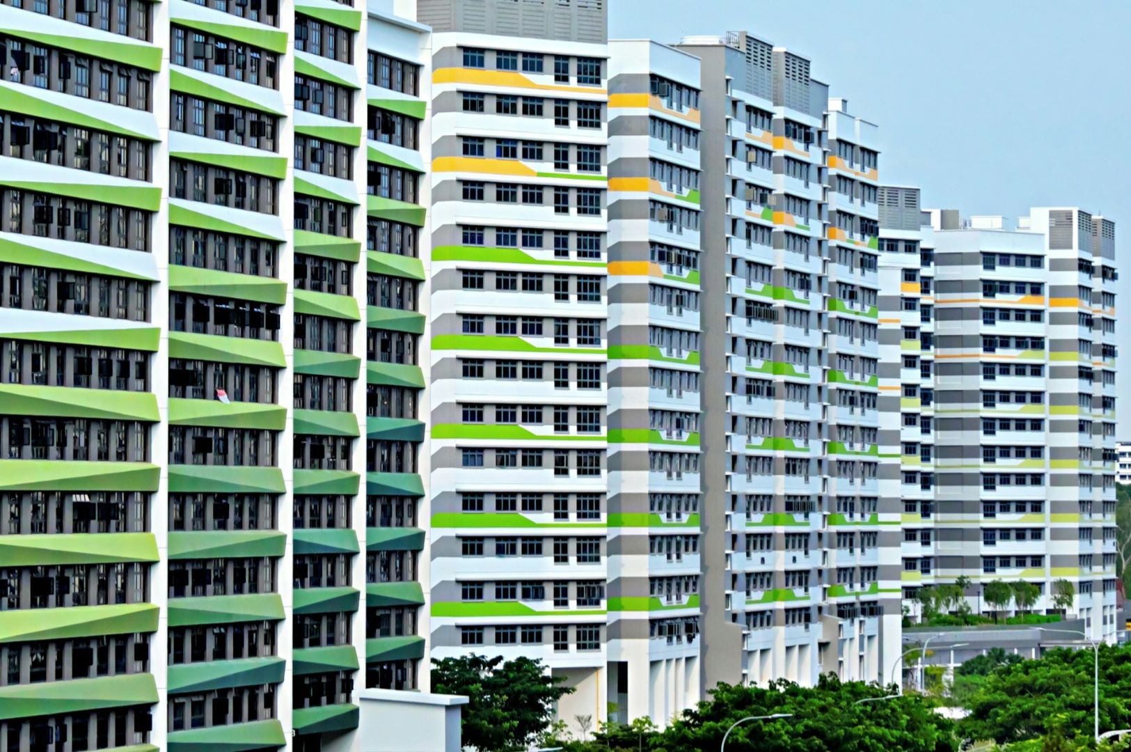 Rows of high-rise apartment buildings with colorful balconies in green, yellow, and purple. The scene conveys urban living and modern architecture.