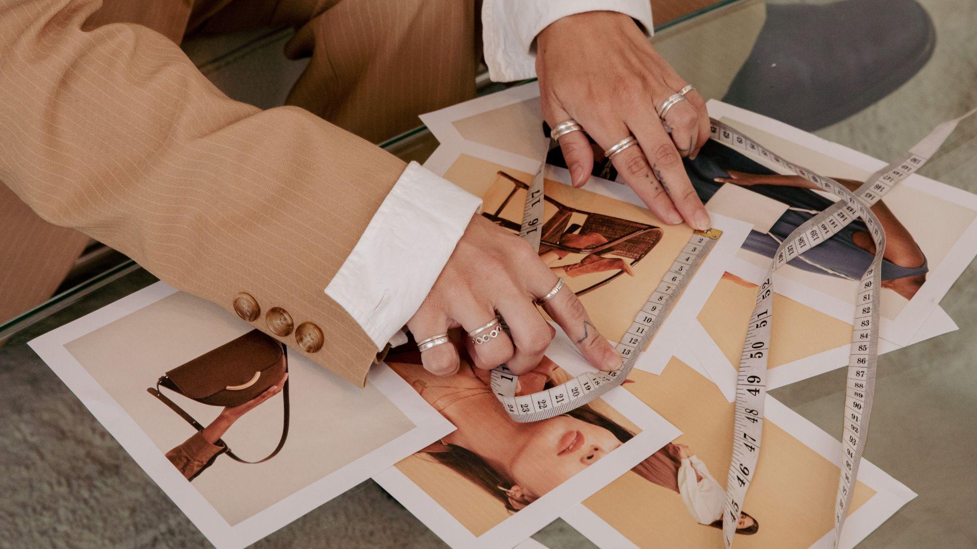 Hands measuring photos with measuring tape.