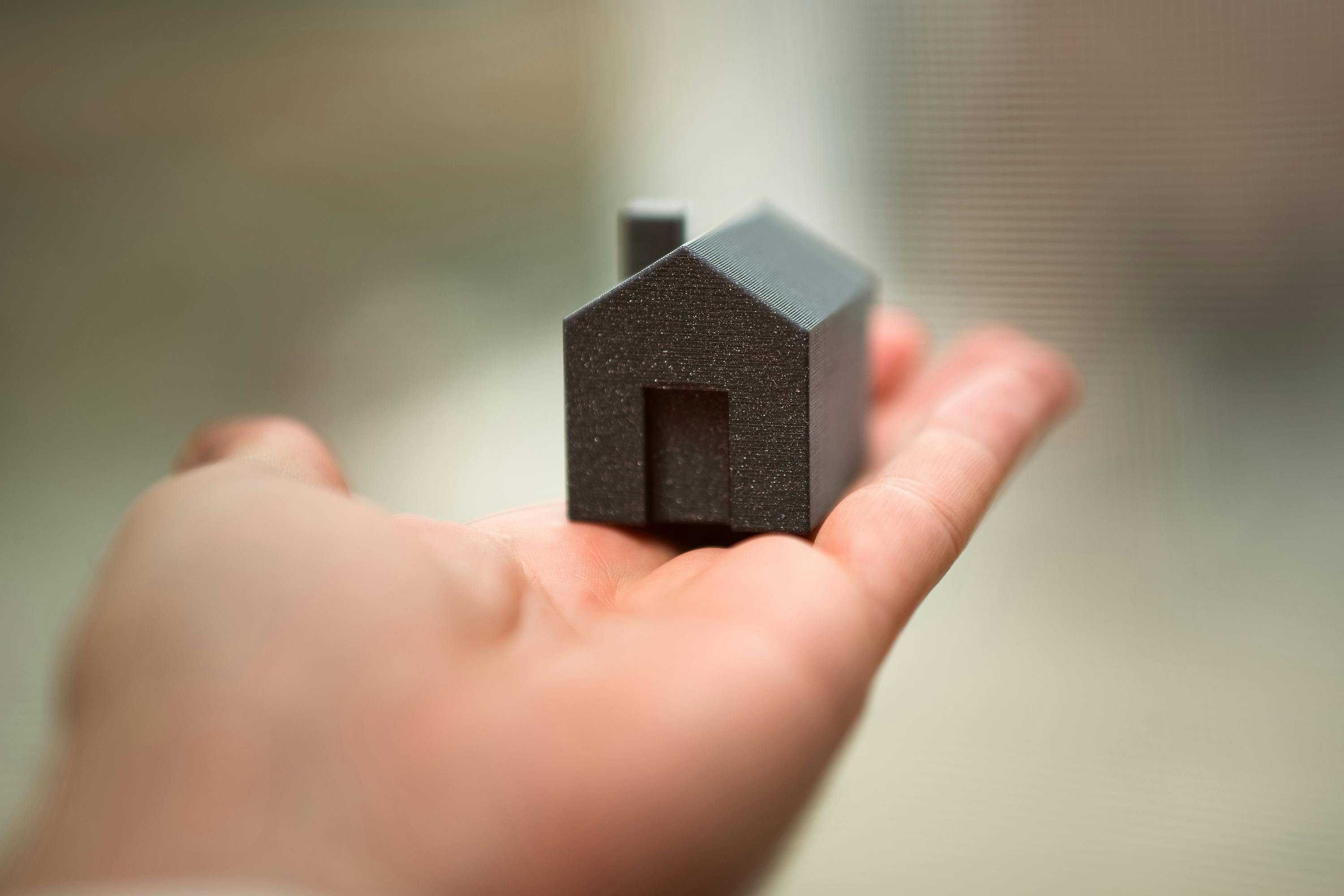 Model of home held in palm. 