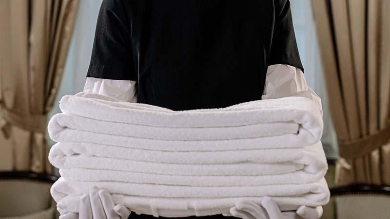 Hotel maid carrying white towels