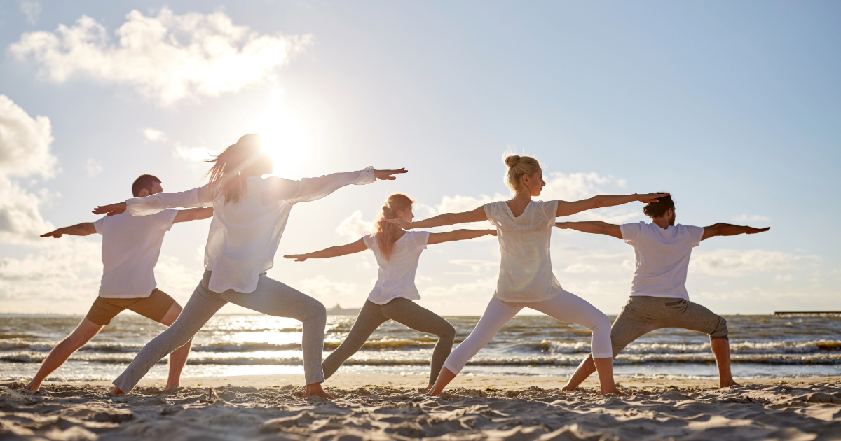 Group of people practicing yoga on the beach at sunrise in North Wildwood, NJ — a popular outdoor activity for visitors staying at Regency Towers.