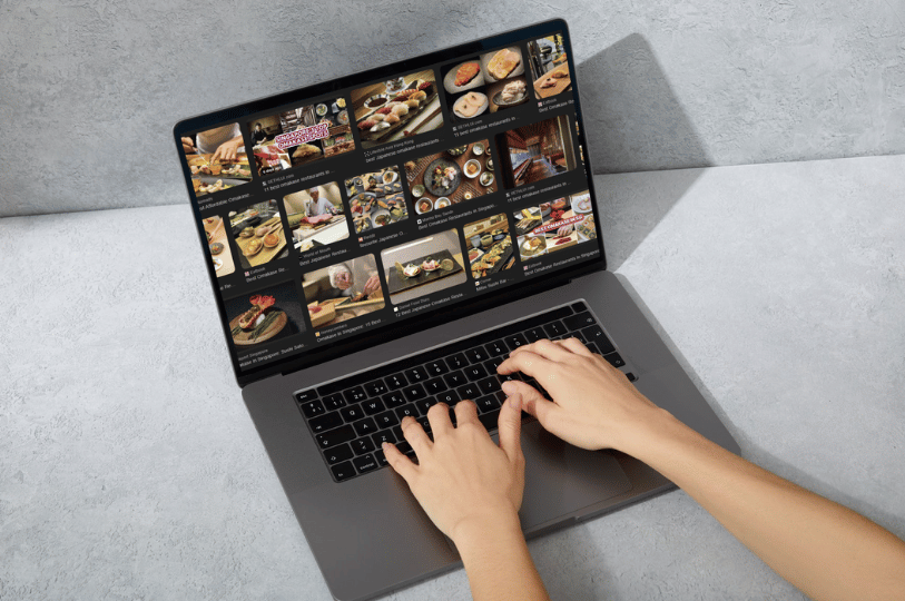 A top-down view of a person’s hands typing on a laptop. The screen displays a grid of high-quality food images from various restaurant websites, emphasizing the importance of visual SEO and image search for restaurants.