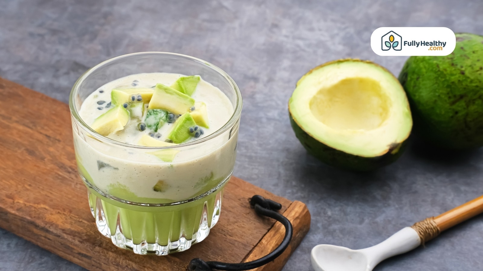 Glass of avocado smoothie with chopped avocado pieces on board