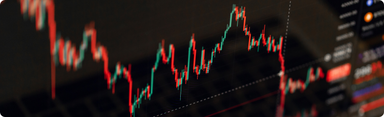 Zbliżenie na wykres finansowy z czerwonymi i zielonymi świecami, pokazujący zmienność cen i trendy rynkowe.)