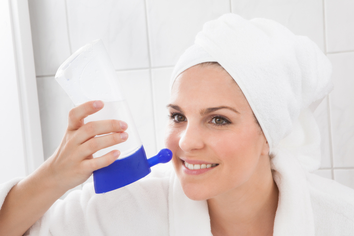 An image of a woman using a neti pot to flush her nasal passages. 