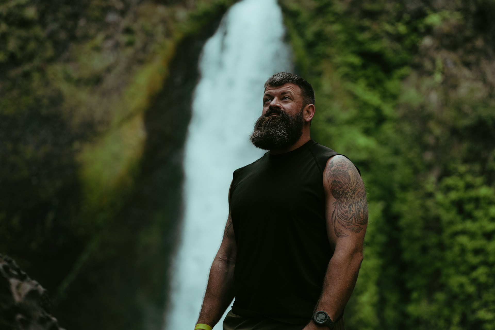 A happy man standing in front of a waterfall