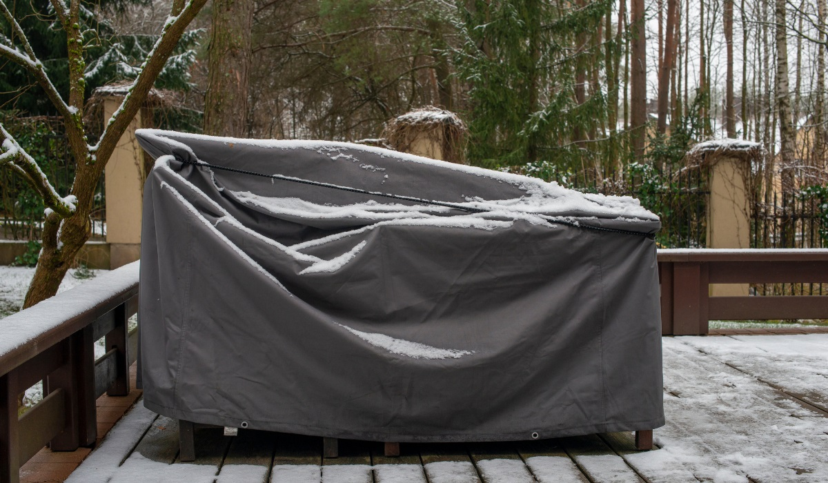 Protecting garden furniture - covered garden furniture on decking in winter - light snow covering 