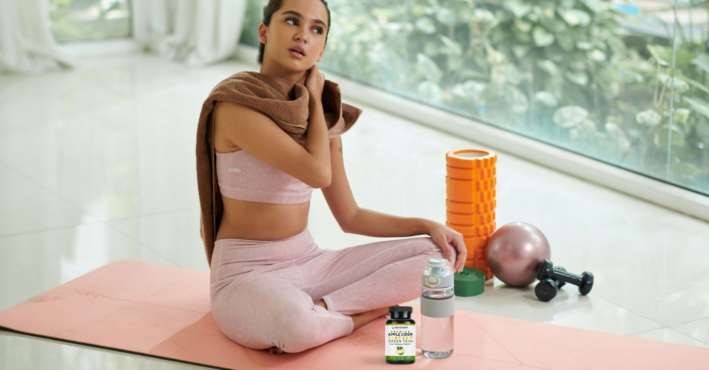 woman relaxing from doing yoga with a trio nutrition's acv + green tea bottle in front of her