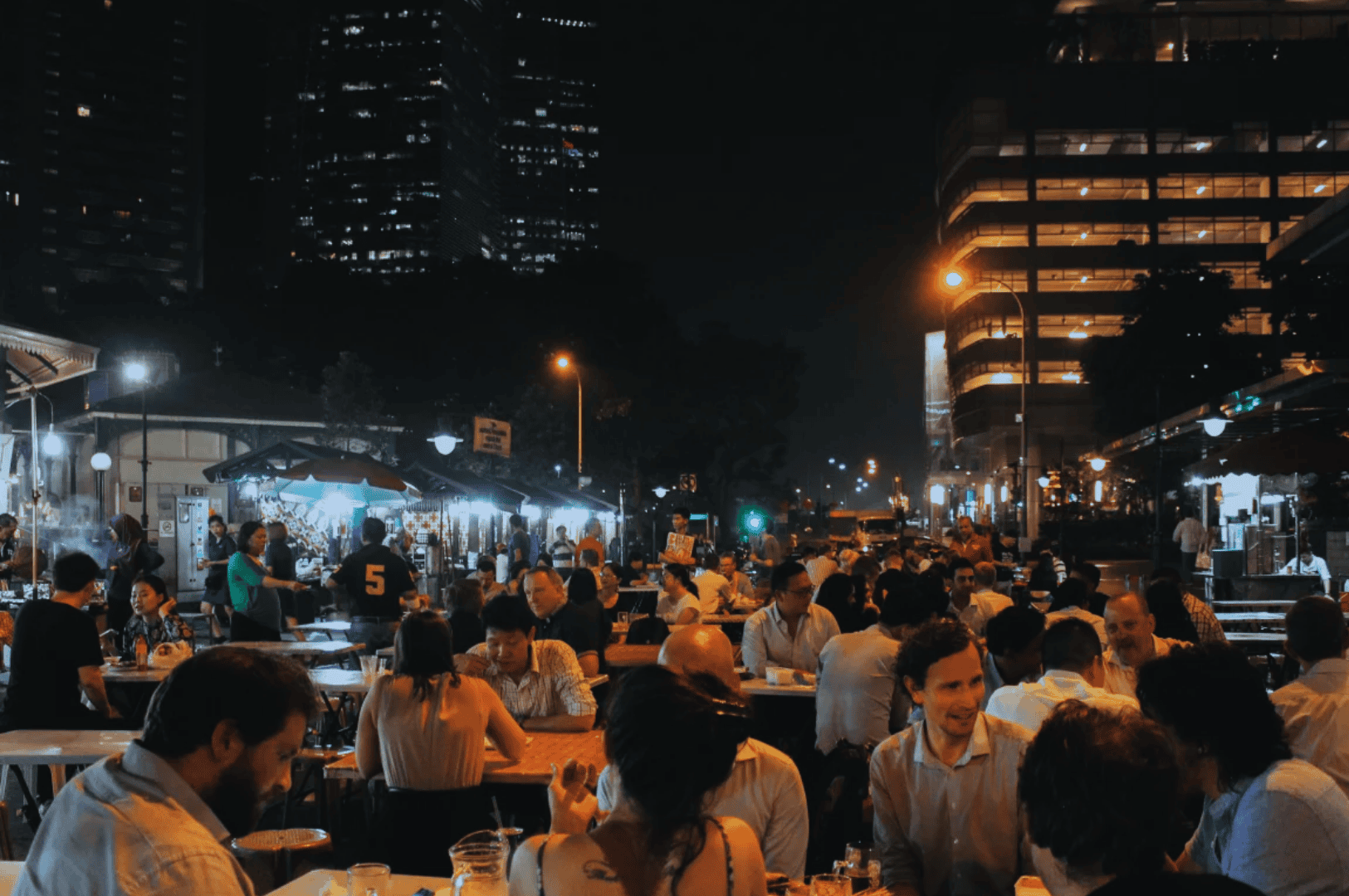 Nighttime scene at one of Singapore's iconic hawker centres, featuring bustling open air food courts with street food vendors and food stalls serving mouthwatering food like char kway teow with chinese sausage, hainanese chicken rice, nasi lemak with coconut milk, and stir fried flat rice noodles topped with bean sprouts, shrimp, egg, and dark soy sauce. Located near the central business district and satay street, this hawker food hub—possibly Lau Pa Sat, Maxwell Food Centre, or Airport Road Food Centre—is a must visit spot for local cuisine and hidden gems. Diners enjoy delicious dishes and drinks like teh tarik and coffee, reflecting hawker culture and the vibrant real life dining experience in southeast Asia. A short walk from Orchard Road or the Singapore River, these hawker centers offer great food at extra cost value, beloved by Anthony Bourdain and locals alike. Perfect for travel tips and blog posts about local dishes, malay dishes, roti prata, hokkien mee, chilli crab, shaved ice, and other ingredients found in Singapore's hawker centers and surrounding islands.