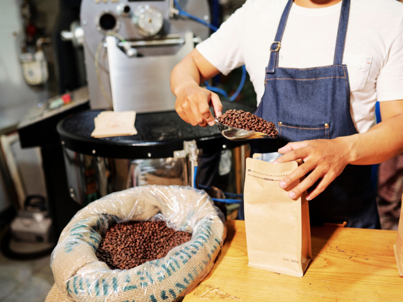Homem embalando grãos de café. Foto: DragonImages - Canva.