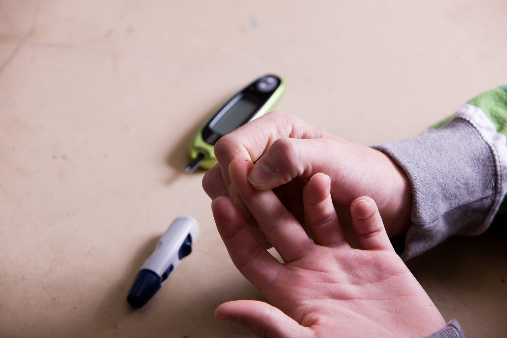 Image of a person checking their blood sugar levels by fingerstick blood glucose value using a traditional glucose meter.