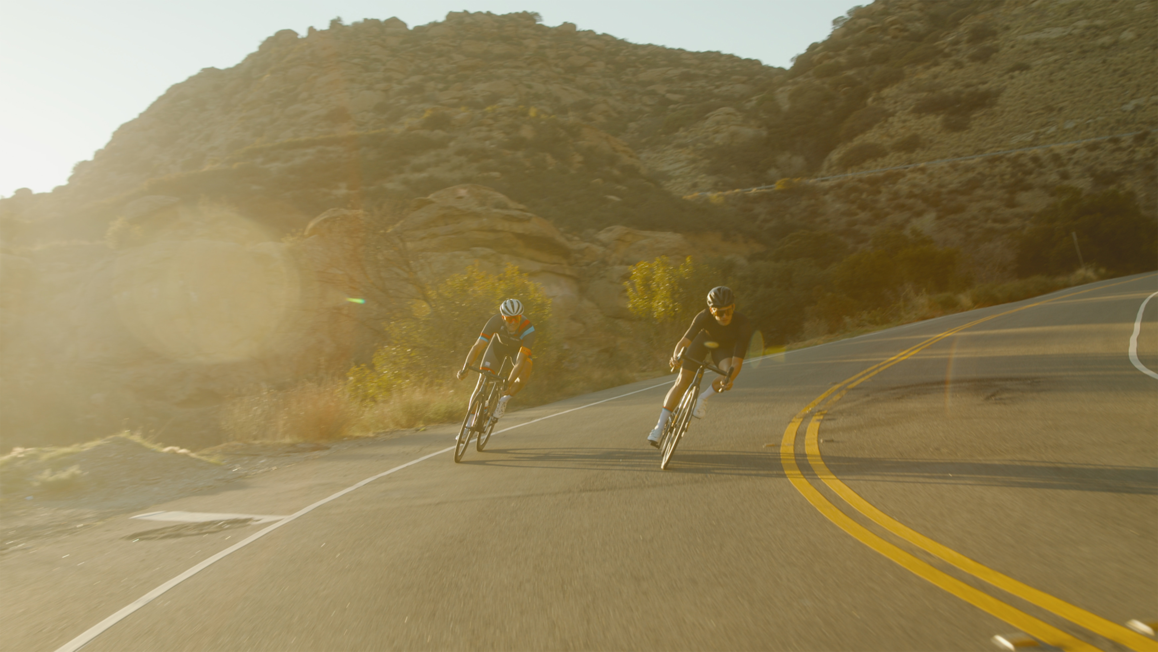 Atletas descendo uma estrada usando bicicletas. Foto de Jack Delulio, Unsplash