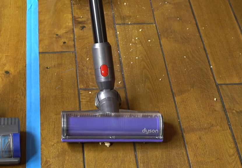 Dyson V8 vacuum picking up cereal on hardwood
