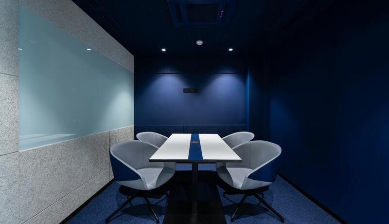 Downlights creating wall wash effect on blue accent wall in meeting room