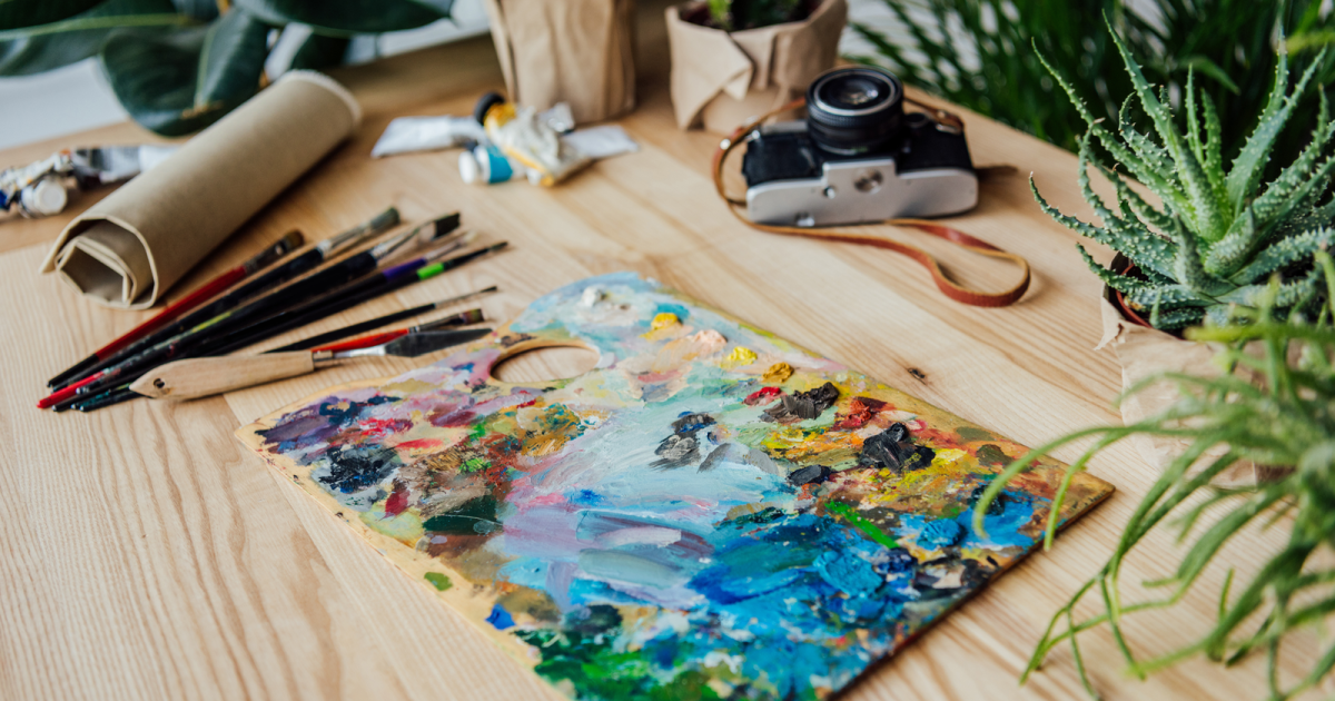 Image of a well-organized personal workspace cluttered with various art supplies such as brushes, paints, sketchbooks, and pencils. This scene represents the concept of personal spaces, underlining the importance of individuality and personal expression within shared living environments.