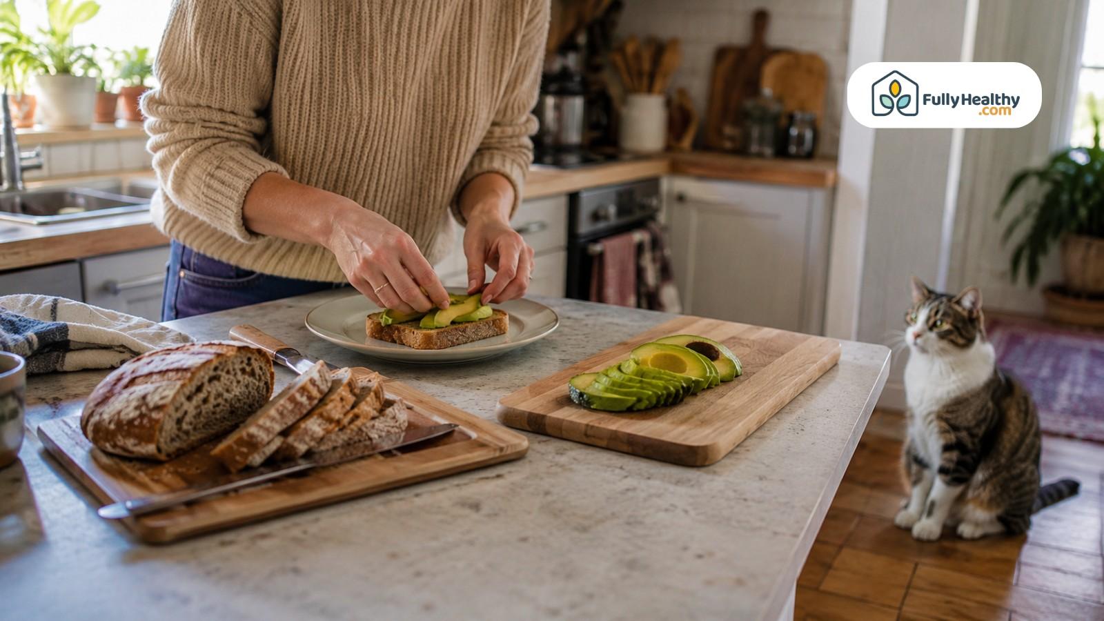 Person preparing avocado toast while cat watches from kitchen floor nearby