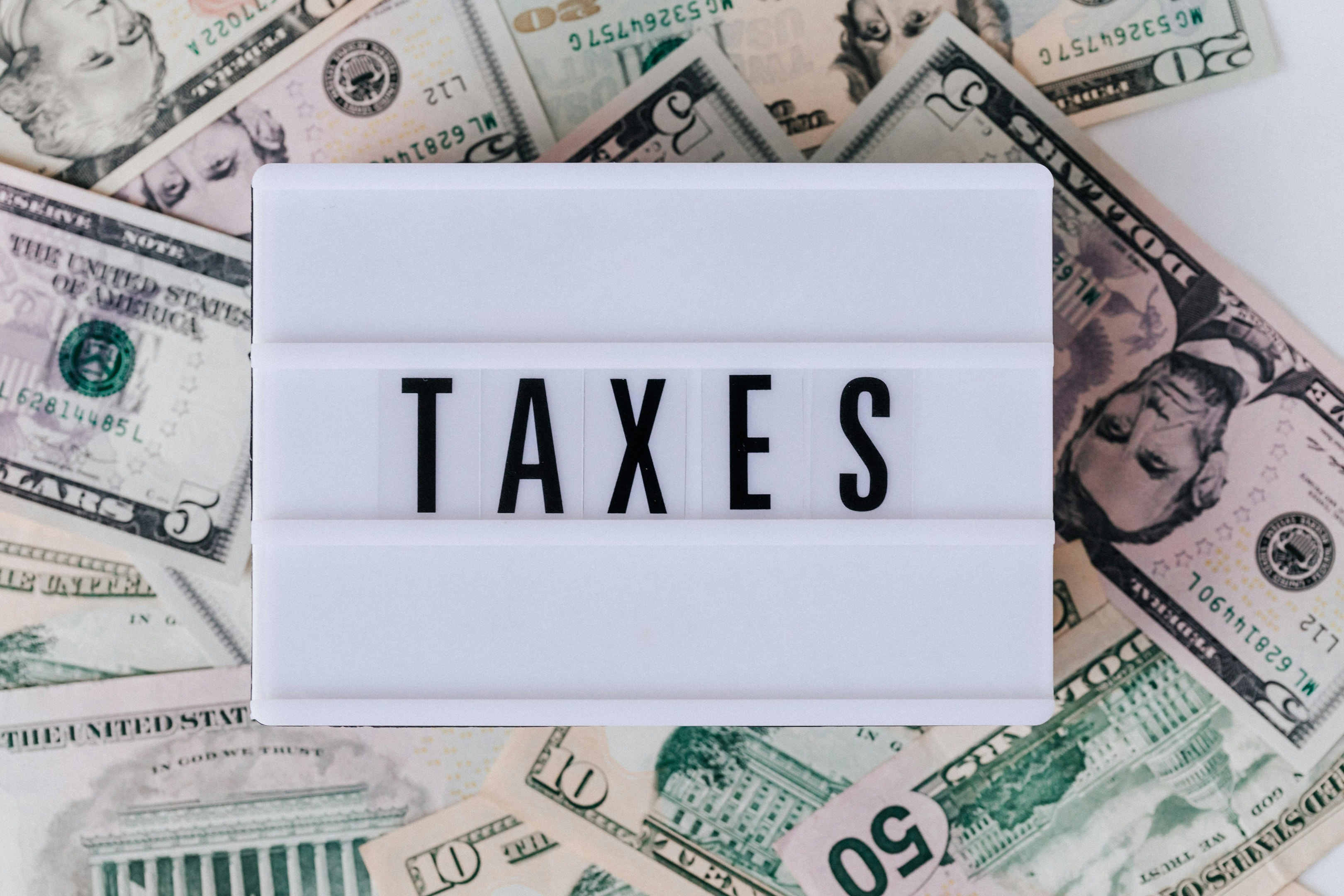 Sign signaling tax season on a pile of various bills.