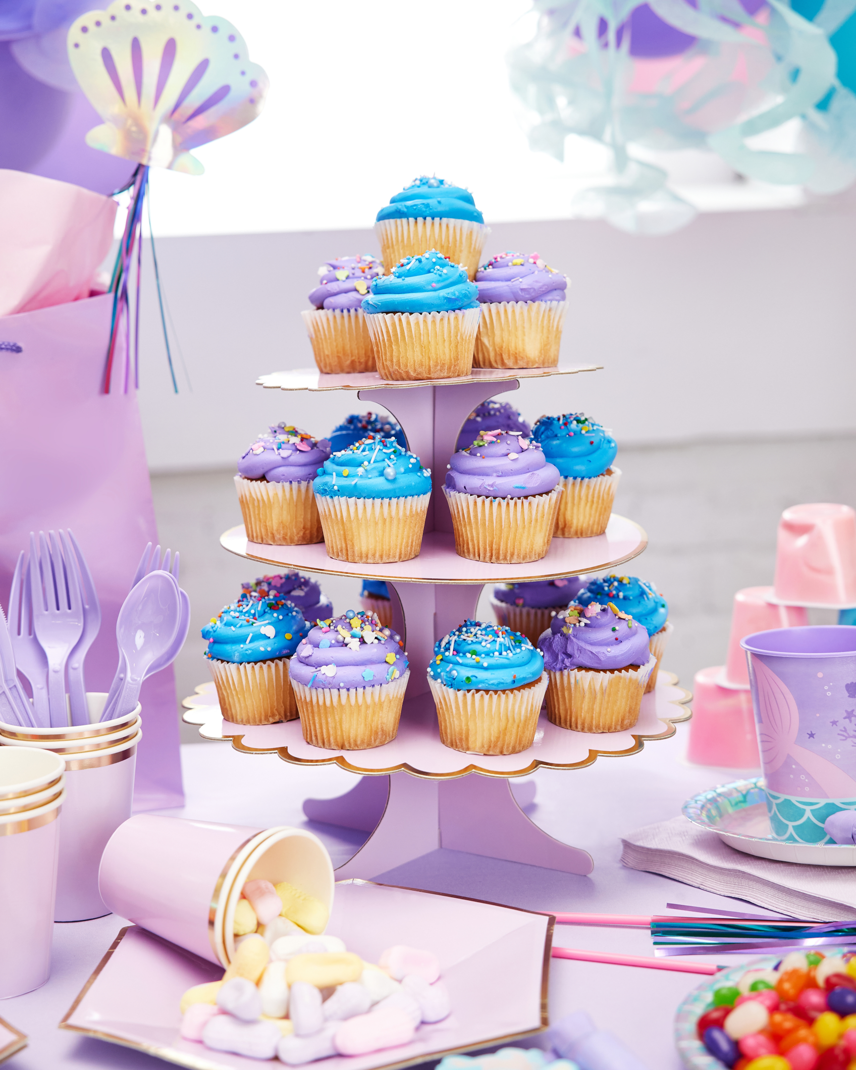 Cupcake stand with blue and purple cupcakes on a mermaid-themed birthday table