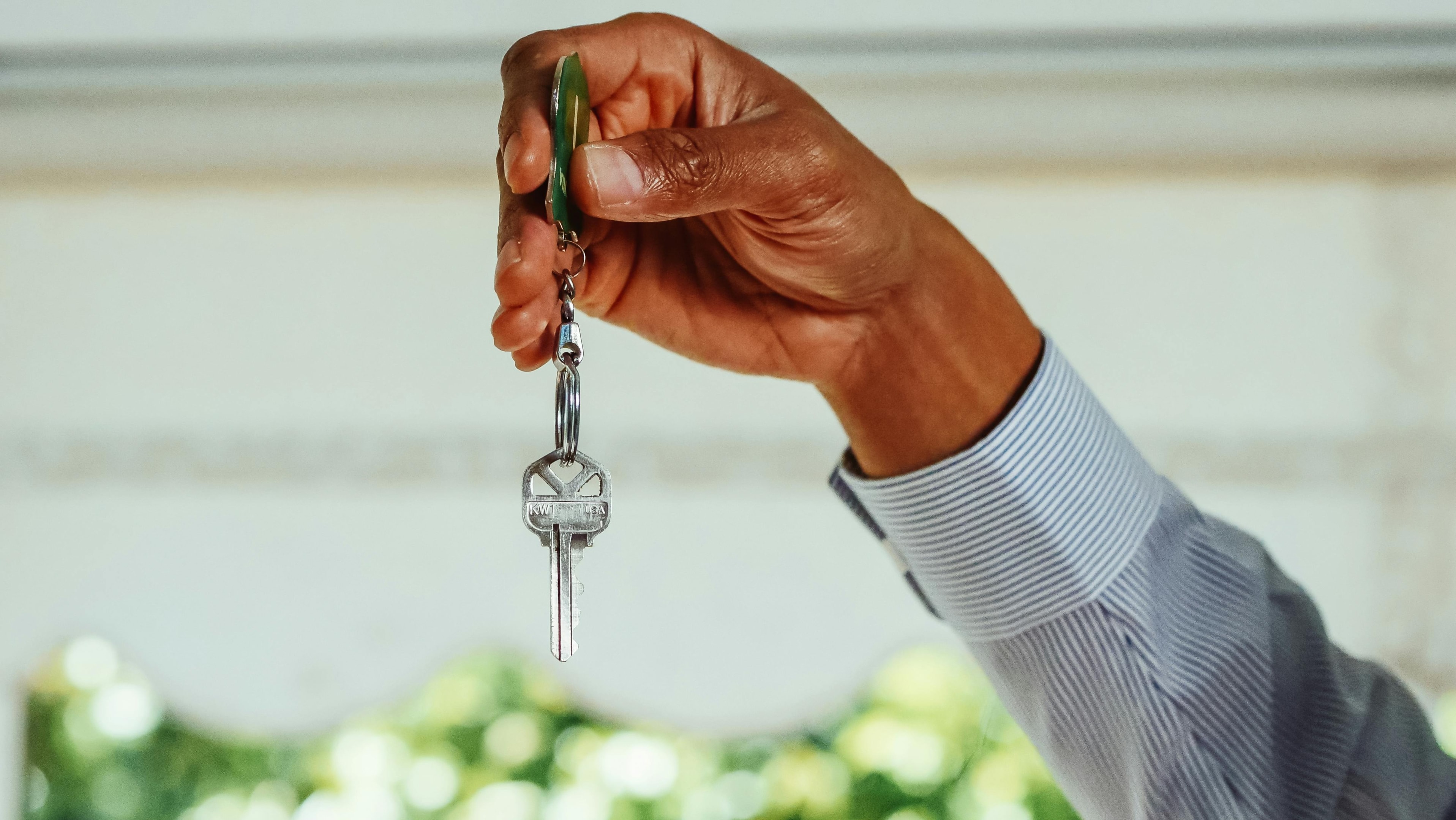 Real estate investor holds house key to distressed property he purchased as an investment property.