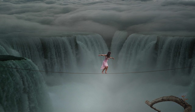 Image by Dieterich01 from Pixabay. Woman tighrope walking over raging waterfalls. Shes wearing pink dress and skies are dark and cloudy. 