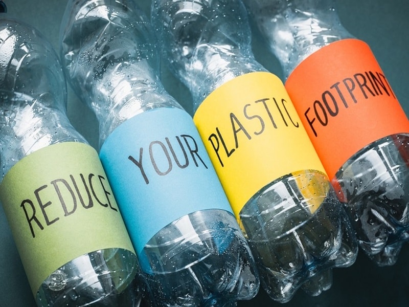 Four plastic bottles with colored labels that say, "Reduce Your Plastic Footprint."