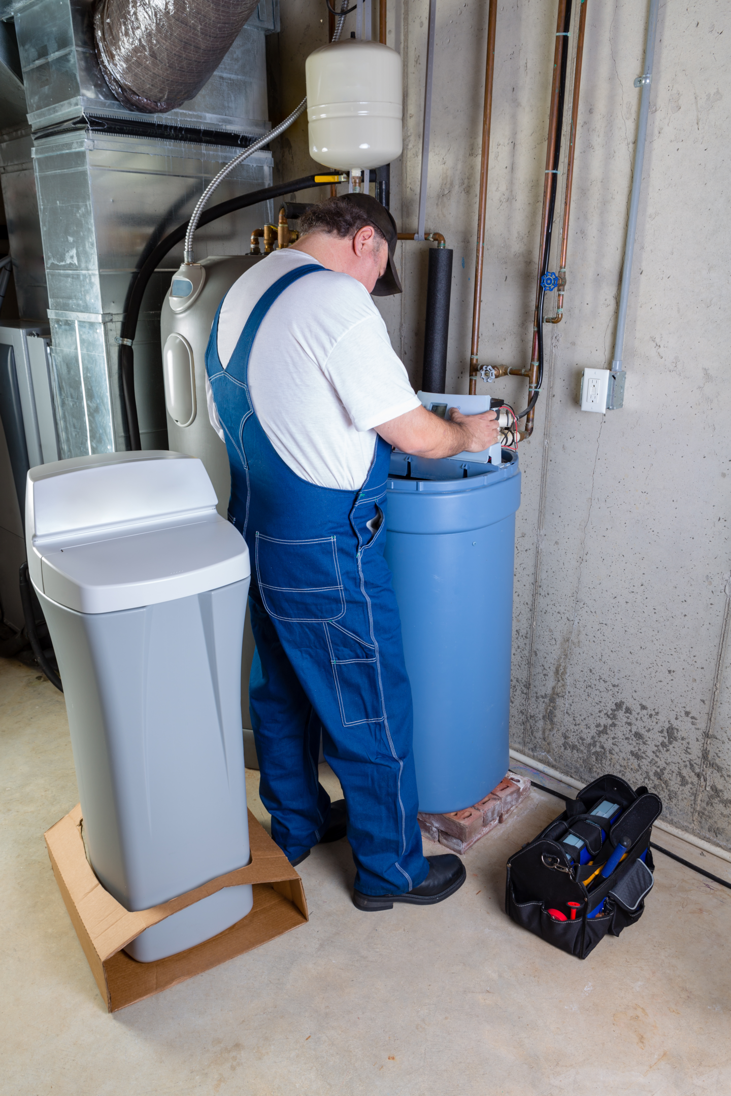 A picture of a plumber performing water softener installation in a residential area