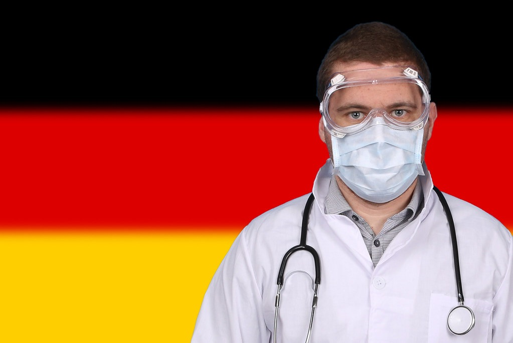 Doctor in protective medical mask over flag of Germany