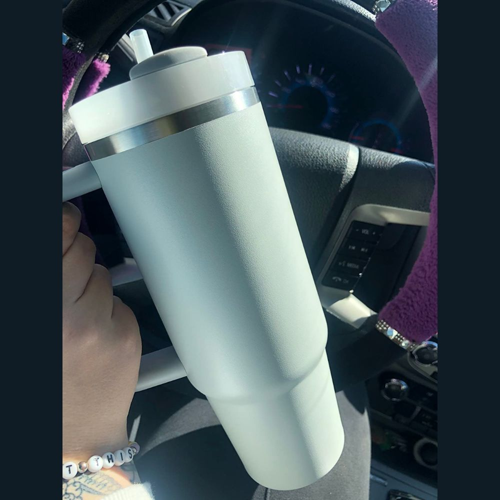 A car cup holder with a Stanley Quencher with a rotating cover and BPA free lid