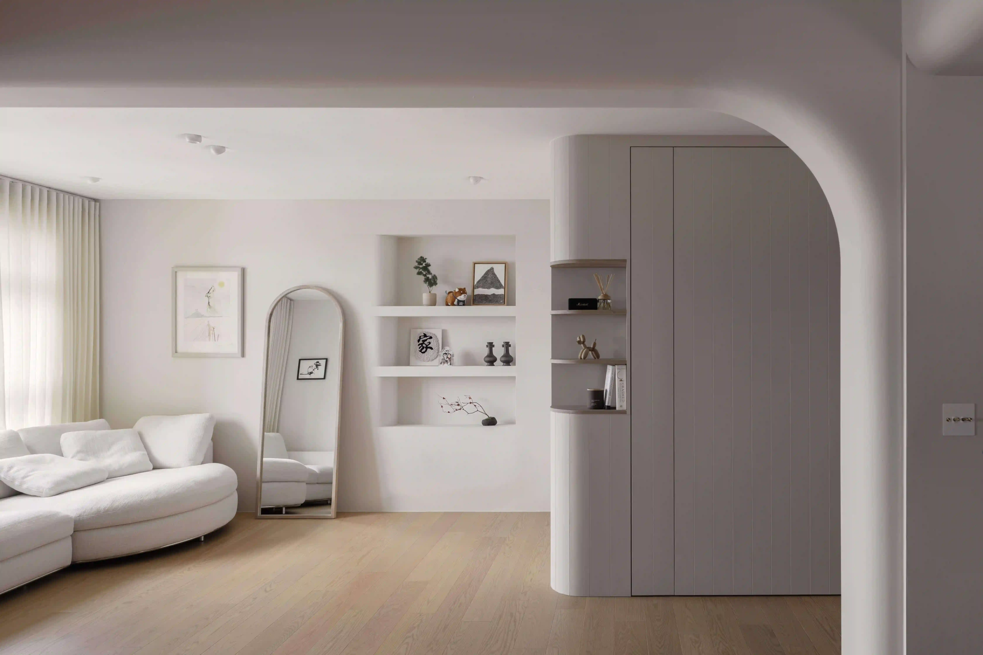 Minimalist BTO living room with curved sofa, built-in shelves and archway wall featuring discreet smart switches