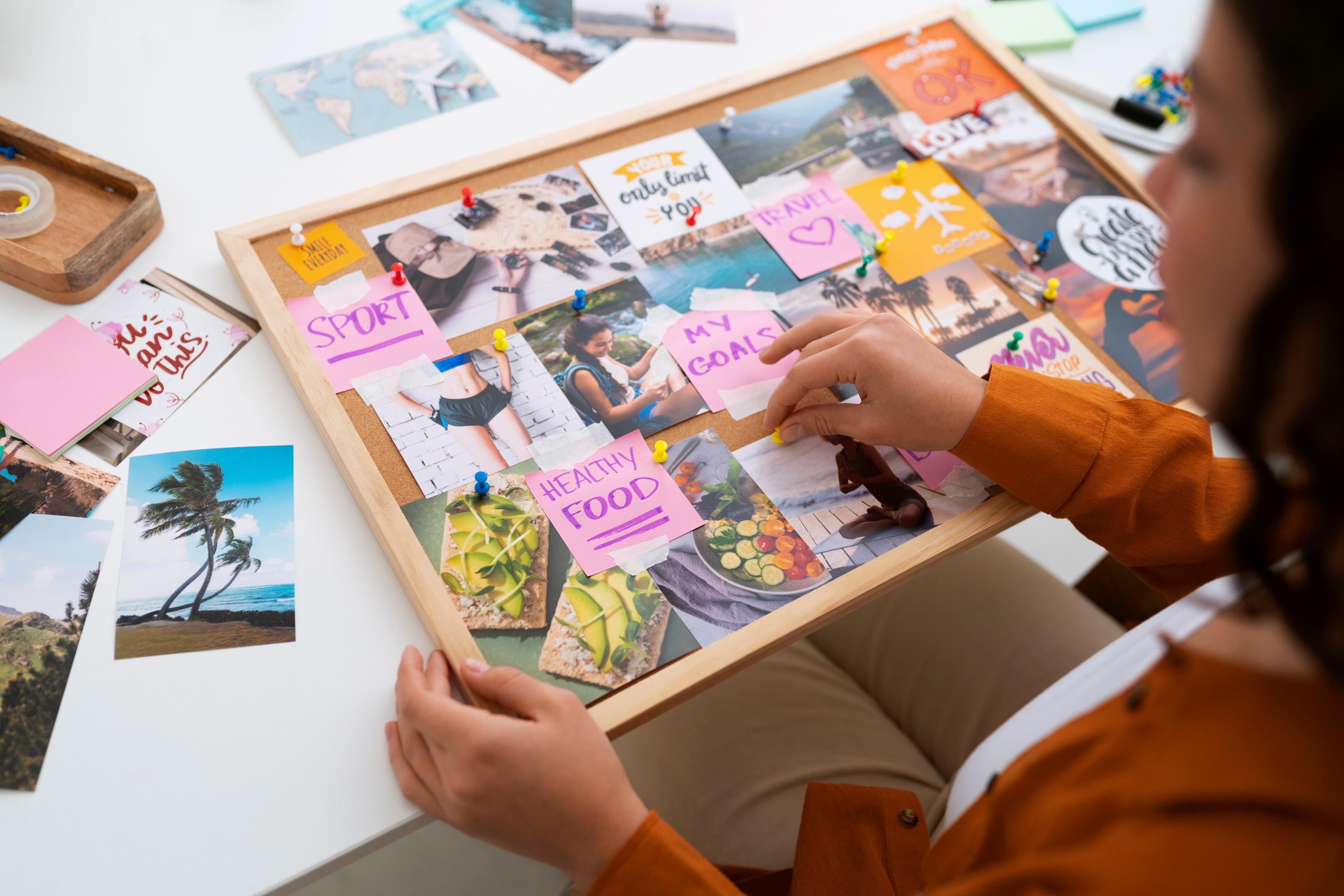 The image depicts a person creating a visual board filled with images and notes that represent significant life events and family history, aimed at illustrating their own life story. This creative process serves as a tool for autobiographical writing, helping to organize thoughts and gain insight into their identity and life journey.