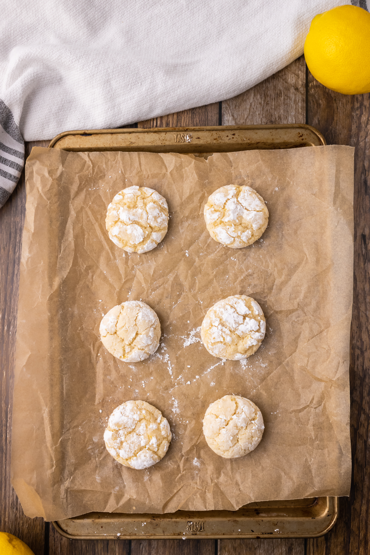 six lemon crinkle cookies on a baking sheet lined with parchment paper