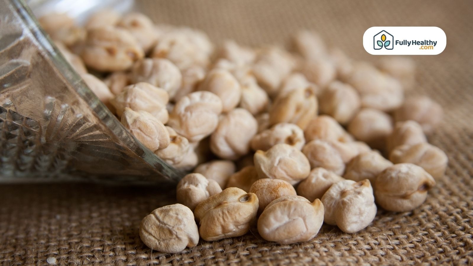 Dried chickpeas spilling from glass jar onto fabric