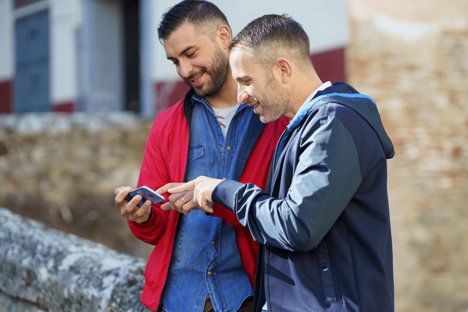 Couple holding smartphone outdoors in New York, seeking resources and guidance to support their ADHD partner in their relationship, fostering a strong bond through mutual understanding and collaboration.