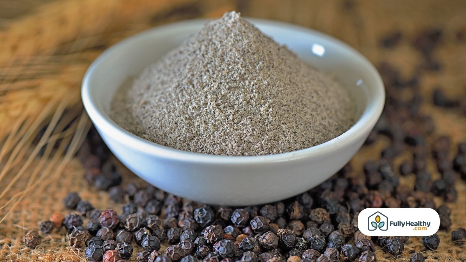 Ground black pepper in a white bowl surrounded by black peppercorns