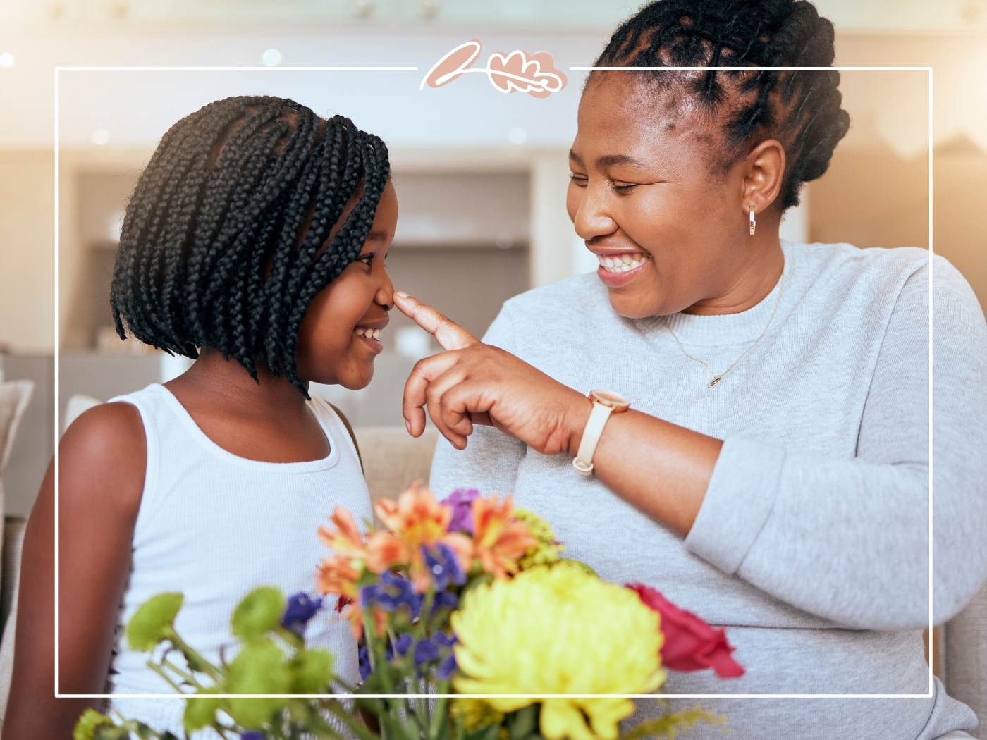 Mother and daughter laughing together with a bouquet of flowers, capturing the spirit of Mother’s Day joy.