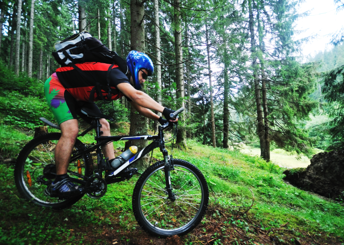 A mountain biker riding a mountain bike on a trail with a full suspension bike