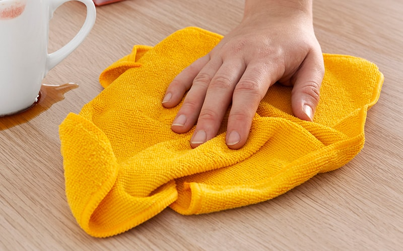 Women Cleaning Table with Yellow Microfiber Towel